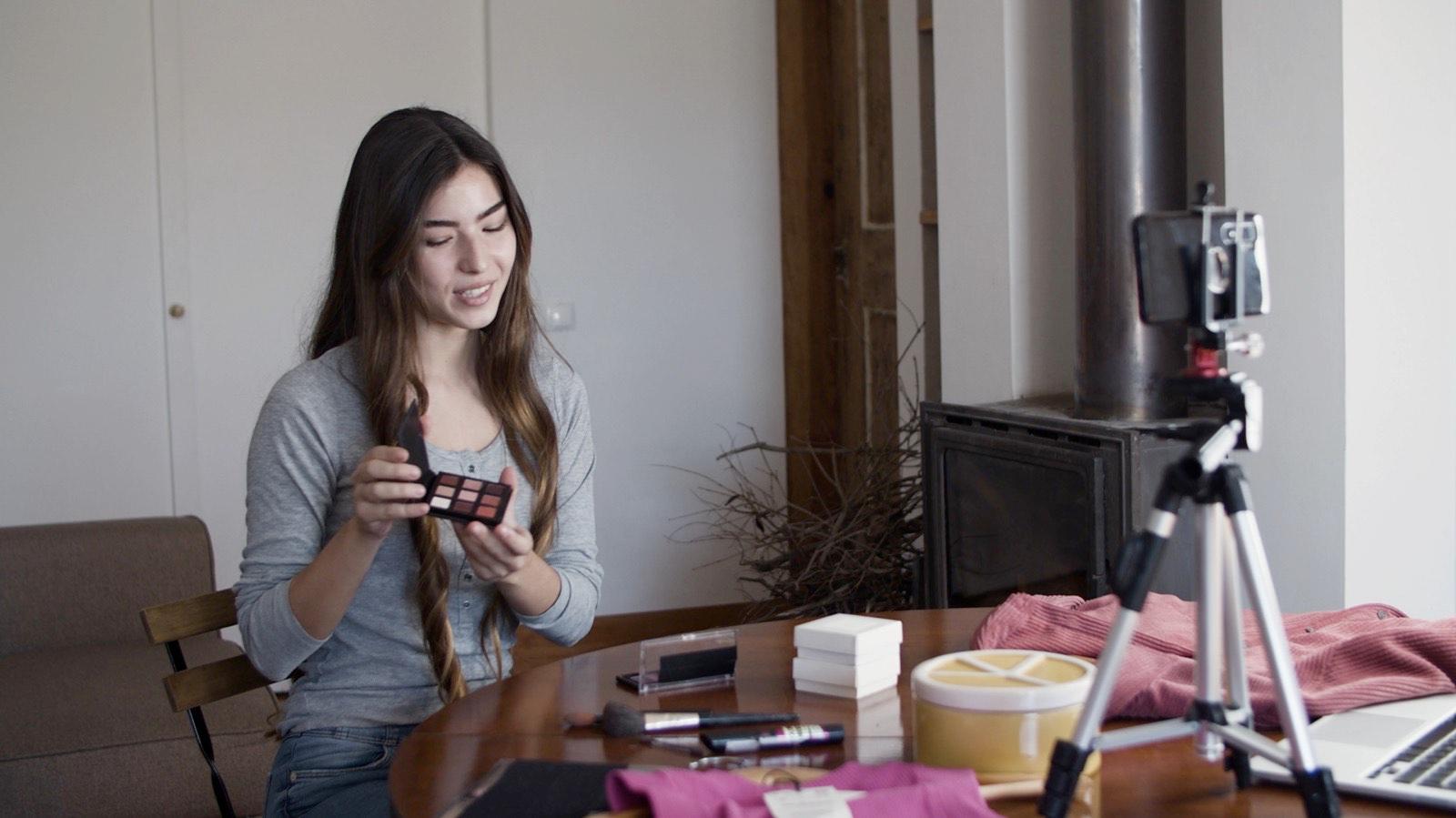 A creator recording a podcast at her desk, with a phone on a tripod